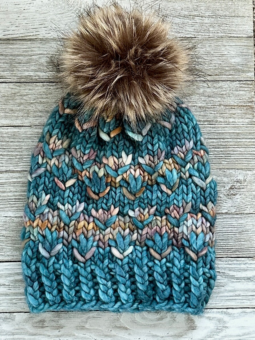 Aquamarine multicolor hand-knit Pomona hat with a brown faux-fur pom
